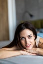 Happy pensive young woman lying and thinking on bed. Thoughtful beautiful girl lying on bed while looking up Royalty Free Stock Photo