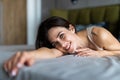 Happy pensive young woman lying and thinking on bed. Thoughtful beautiful girl lying on bed while looking up Royalty Free Stock Photo