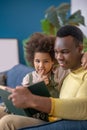 African american reading book to his hugging daughter