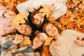 Happy people. Autumn portrait. Happy young women students playing with leaves, smiling while lying on ground in park Royalty Free Stock Photo