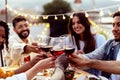 Happy people celebrating summer party toasting with red wine at home terrace.