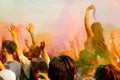 Happy people crowd partying under colorful powder cloud at holi