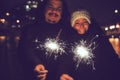 Happy people enjoying fireworks outdoors. Couple with sparklers at night Royalty Free Stock Photo