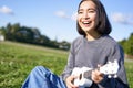 Happy people and hobbies. Smiling asian girl playing ukulele guitar and singing, sitting in park outdoors on blanket Royalty Free Stock Photo