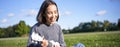 Happy people and hobbies. Smiling asian girl playing ukulele guitar and singing, sitting in park outdoors on blanket Royalty Free Stock Photo