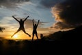 Happy people jumping over sunset, concept having fun and joy. Two silhouettes and a beautiful sunset Royalty Free Stock Photo