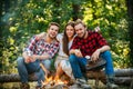 Happy people sitting around campfire. Friends roasting hotdogs on sticks at bonfire and having fun at camp fire. Summer Royalty Free Stock Photo