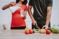 A pregnant woman is preparing food with her husband.