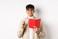 Happy person in glasses writing in journal, holding pen and diary, smiling at camera, plan a schedule, standing with Royalty Free Stock Photo