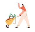 Happy person going, carrying wheelbarrow with soil and plants. Eco volunteer with tree seedlings. Man with spring Royalty Free Stock Photo