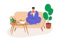 Happy person relaxing at home, sitting on sofa, warming with tea cup. Man resting on cozy couch, wrapped in blanket in