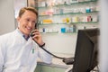 Happy pharmacist on the phone using computer