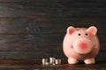 Happy piggy bank with money on wood table against wooden background, space for text