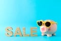 Happy piggy bank with sunglasses and inscription SALE on color background, space for text Royalty Free Stock Photo