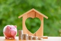 Happy Pink Piggy Bank and Home wooden in close-up and coins stack in the nature background, Saving ideas  and investment budget, B Royalty Free Stock Photo