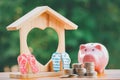 Happy Pink Piggy Bank and Home wooden in close-up and coins stack in the nature background, Saving ideas  and investment budget, B Royalty Free Stock Photo