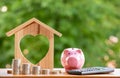 Happy Pink Piggy Bank and Home wooden in close-up and coins stack in the nature background, Saving ideas  and investment budget, B Royalty Free Stock Photo