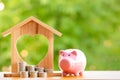 Happy Pink Piggy Bank and Home wooden in close-up and coins stack in the nature background, Saving ideas and investment budget, Bu Royalty Free Stock Photo