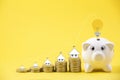 Happy Pink Piggy Bank and Light bulb in close-up and house icon on coins stack on yellow background, Royalty Free Stock Photo