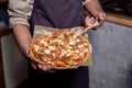 Happy pizza delivery man showing fresh pizza in a commercial kitchen Royalty Free Stock Photo