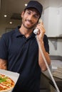 Happy pizza delivery man taking an order over the phone Royalty Free Stock Photo