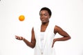 Happy playful african woman thowing orange up in the air