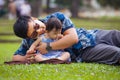 Happy playful Asian Korean man as loving father enjoying sweet and beautiful baby girl daughter sitting together playing on grass Royalty Free Stock Photo