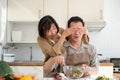 A happy, playful Asian wife is teasing her husband while he is cooking. Peek a boo Royalty Free Stock Photo