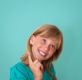 Happy playful child smiling happy and joyful on turquoise background. Thinking beautiful girl looking to the side Royalty Free Stock Photo