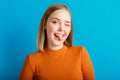 Happy playful teen girl showing tongue and blink. Emotional portrait of grimace young woman funny girl winking and Royalty Free Stock Photo