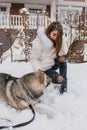 Happy playful time of excited joyful young woman having fun with husky dog on the street in snow. Happy winter time with Royalty Free Stock Photo