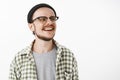 Happy pleased and delighted lucky male skater boy in black beanie glasses and checked casual shirt looking right with Royalty Free Stock Photo