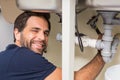 Happy plumber fixing under the sink Royalty Free Stock Photo