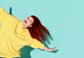 Happy plump female with flowing red hair dancing or jumping with her arms outstretched widely like wings.