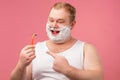 Happy plump man with shaving foam on his face and razor isolated on pink Royalty Free Stock Photo