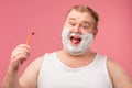 Happy plump man with shaving foam on his face and razor isolated on pink Royalty Free Stock Photo