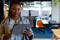 Happy plus size african american casual businesswoman using tablet in office, copy space Royalty Free Stock Photo