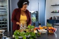 Happy plus size african american woman preparing dinner, chopping vegetables in kitchen Royalty Free Stock Photo