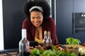 Happy plus size african american woman using smartphone, preparing food in kitchen Royalty Free Stock Photo