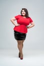 Happy plus size fashion model in red blouse and black skirt, fat woman on gray background, body positive concept Royalty Free Stock Photo