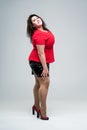 Happy plus size fashion model in red blouse and black skirt, fat woman on gray background, body positive concept Royalty Free Stock Photo