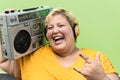 Happy plus size woman having fun listening music with wireless headphones and boombox stereo