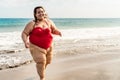 Happy plus size woman running on the beach - Curvy overweight model having fun during vacation in tropical destination