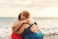 Happy plus size women hugging on the beach - Curvy overweight girls having fun during vacation