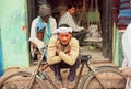 Happy poor man sitting with his cycle on the street