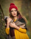 Happy Portrait fashion of a beautiful young Caucasian woman with a red cap and scarf and yellow pullover in autumn park,red green Royalty Free Stock Photo