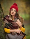 Happy Portrait fashion of a beautiful young Caucasian woman with a red cap and scarf and yellow pullover in autumn park,red green Royalty Free Stock Photo