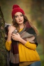 Happy Portrait fashion of a beautiful young Caucasian woman with a red cap and scarf and yellow pullover in autumn park,red green Royalty Free Stock Photo