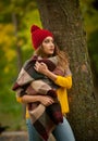 Happy Portrait fashion of a beautiful young Caucasian woman with a red cap and scarf and yellow pullover in autumn park,red green Royalty Free Stock Photo