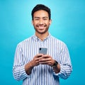 Happy, portrait and a man with a phone for communication isolated on a blue background in a studio. Smile, social media